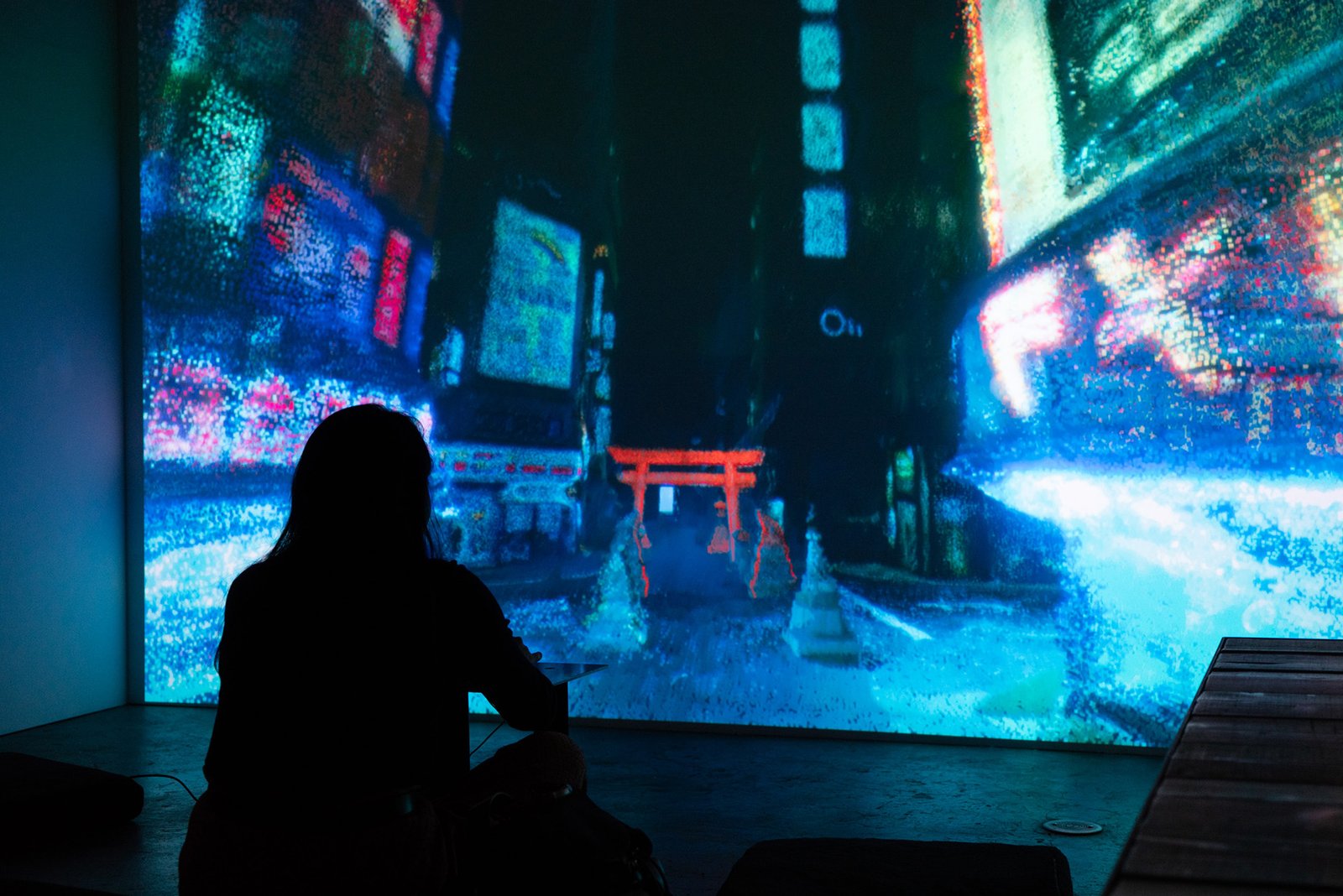 A person silhouetted before a wall-sized projection of a city street rendered as a glowing point cloud