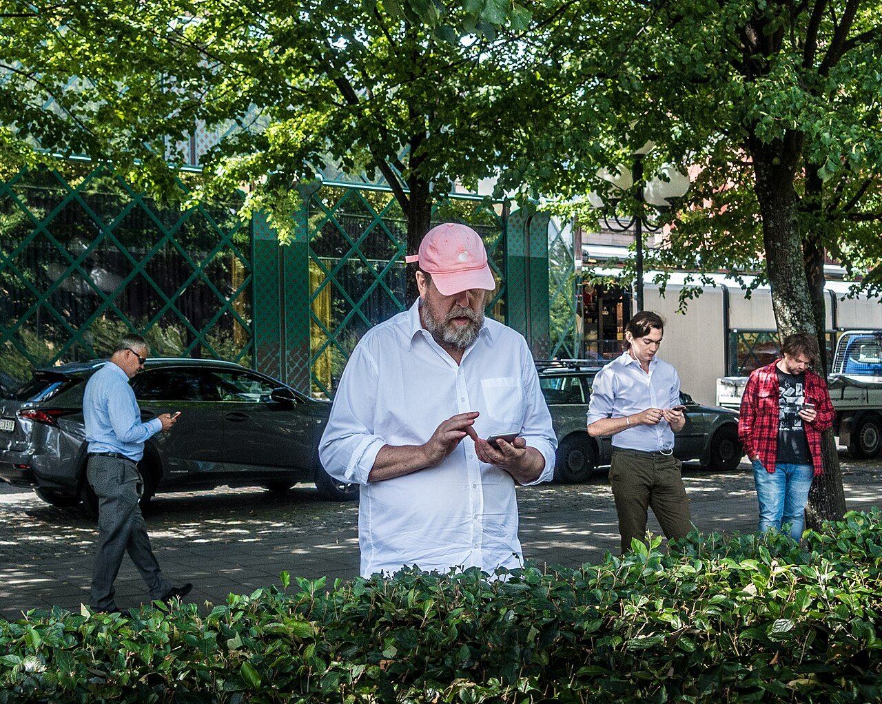 Four people standing on a street corner, each absorbed in their phone, playing Pokémon GO