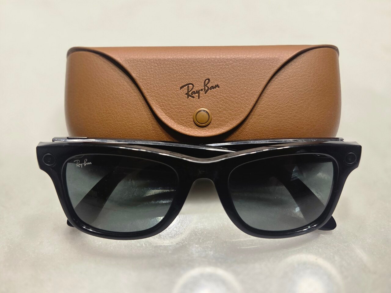 Ray-Ban Meta smart glasses resting against their tan charging case